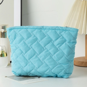 Detail of light blue quilted makeup bag showing woven texture and zipper closure