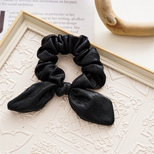 Close-up of black ribbed fabric hair scrunchie with bowknot in decorative frame