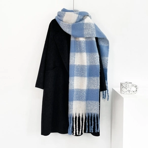Detailed view of blue and white plaid mohair scarf with fringes on a black coat