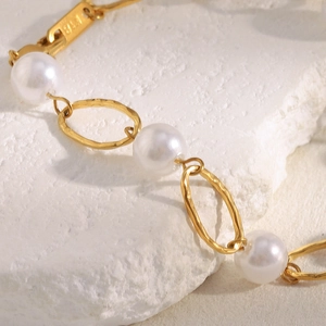 Detailed view of 18K gold plated hammered metal chain with elegant white pearls