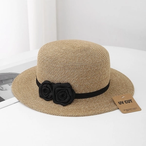 Detail of boater hat featuring black silk ribbon, fabric roses, and UV protection tag