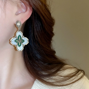 Détail macro de boucles d'oreilles vintage émaillées avec motif floral et cadre doré