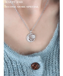 Detail of silver sun and moon pendant necklace worn on a light blue knitted sweater