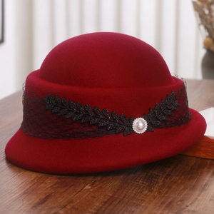 Détail d'un chapeau cloche en feutre rouge avec dentelle noire et perle élégante