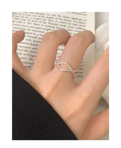 Detail of S925 sterling silver twisted hollow ring worn on finger over an English book