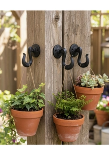 Vintage black cast iron J-hook mounted on wooden post hanging ceramic plant pots