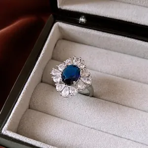 French palace style cluster ring with blue drop zircon and silver metal on red silk