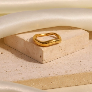 Vue détaillée d'une bague dorée ondulée irrégulière sur un piédestal en pierre naturelle