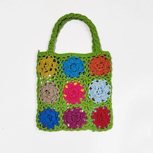 Close-up of colorful crochet flower bag with green base and detailed stitching texture