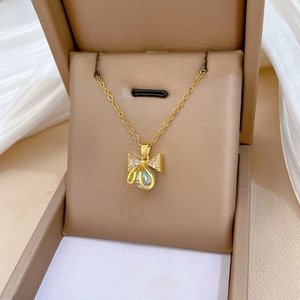 Macro view of gold bow pendant with sparkling crystals and elegant white pearl detail