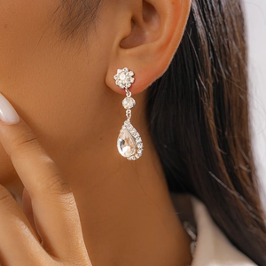 Détail de boucles d'oreilles argentées avec cristaux en goutte et design floral sur un mannequin