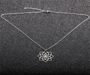 Détail d'un pendentif lotus évidé en argent sur une fine chaîne sur fond noir