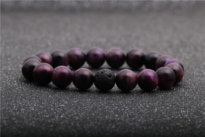 Macro detail of purple tiger eye beads and black lava stone on a shimmering background