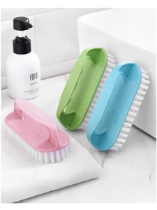 Close-up of three colorful household cleaning brushes with ergonomic handles on a counter