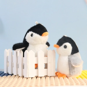 Close-up of cute black and gray plush penguin keychains on a colorful block background
