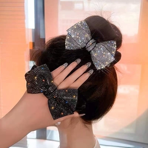 Detail of sparkling bow hair claws with full rhinestones shown on a hair bun