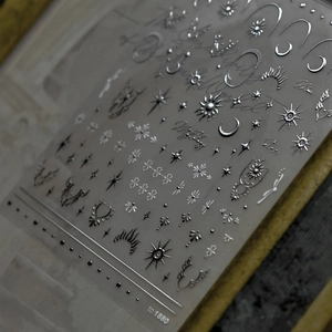 Macro detail of silver laser nail art stickers with moon and star embossed patterns