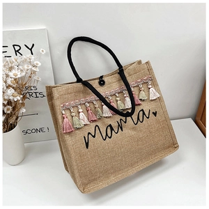 Detail of jute tote bag with Mama print, bohemian colorful tassels and black rope handles