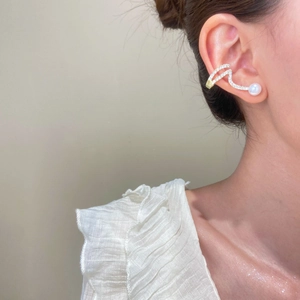 Vue détaillée du ear cuff ondulé orné de zircons et d'une perle blanche sur l'oreille