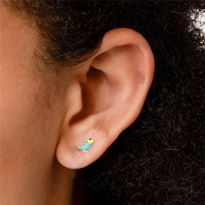 Close-up of a blue bird stud earring featuring colorful enamel detail on a model's ear