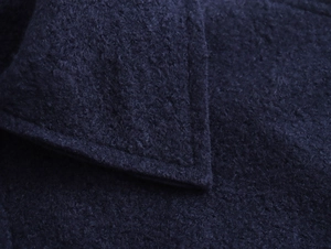 Gros plan sur la texture bouclée bleu foncé et les coutures d'une veste courte femme