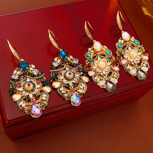 Close-up of vintage crystal teardrop earrings in gold setting on a dark wooden box