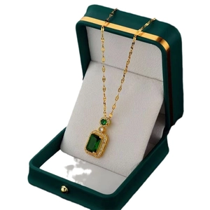 Elegant gold necklace with emerald-cut green gemstone in a luxury velvet jewelry box