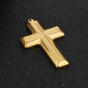 Detailed close-up of a golden stainless steel cross pendant on black textured surface