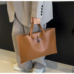 Detail of dark brown leather tote bag with elastic loop closure held by business model