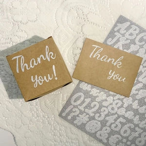 Macro view of silver glitter alphabet and number stickers on lace with thank you card