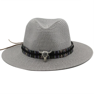 Detail of grey straw fedora featuring an ethnic ribbon and a metal bull head ornament