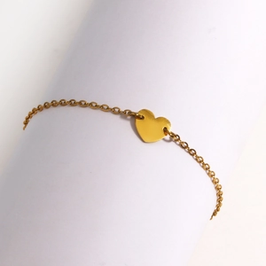 Gros plan détaillé d'un pendentif en forme de cœur doré sur un bracelet chaîne minimaliste
