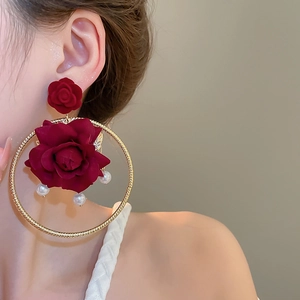 Detail of red fabric rose earring with gold hoop and hanging white pearls on model