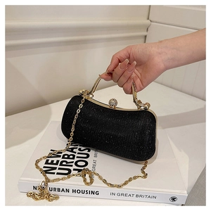 Detail of black glitter evening clutch with gold handle and sparkling diamond clasp