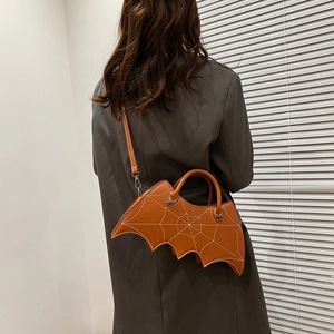 Brown bat-wing shaped PU leather crossbody bag worn by a model in a grey blazer