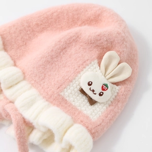 Close-up of pink baby plush hat featuring a cute white rabbit embroidery detail
