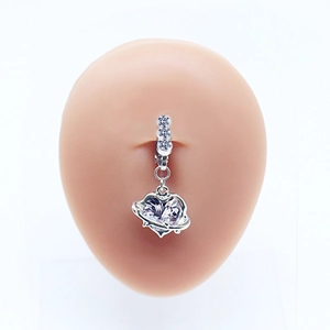Détail d'un piercing de nombril planète cœur en argent avec zircon sur modèle de peau