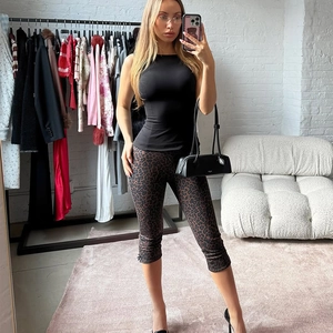 Mirror selfie showing black sleeveless crop top and leopard print leggings set