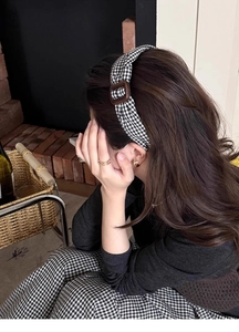 Gros plan d'un serre-tête à carreaux noir et blanc avec boucle marron sur un modèle
