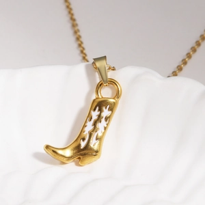 Gros plan détaillé d'un pendentif botte de cow-boy dorée avec motif ajouré blanc sur un coquillage
