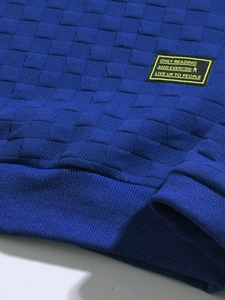 Detail of blue checkerboard textured fabric on long sleeve shirt with ribbed hem