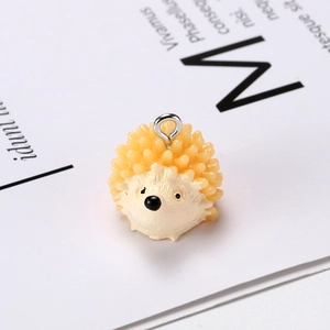Macro shot of a cute yellow and beige resin hedgehog pendant with a metal ring hook