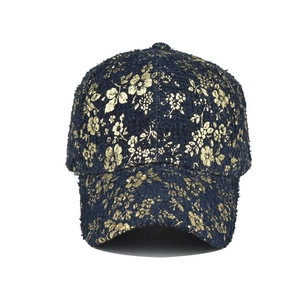 Detail of high-quality dark tweed baseball cap with intricate gold floral print patterns