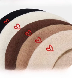 Detail of wool blend berets in five colors with delicate red heart embroidery accents