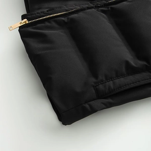 Detailed macro view of high-quality gold metal zipper on black quilted puffer jacket