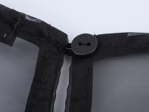 Détail du col en organza noir avec texture en maille et bouton rond élégant