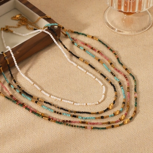 Close-up of colorful natural stone beaded necklaces with stainless steel accents on linen