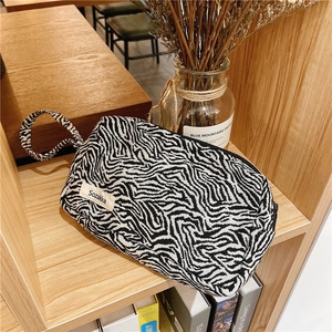 Gros plan d'une trousse à maquillage en toile zébrée avec étiquette et dragonne assortie