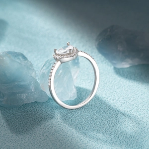 Detailed view of heart-shaped crystal ring with sparkling diamonds on blue textured surface
