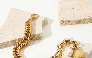 Macro shot of 18K gold plated Cuban chain bracelet with freshwater pearl and shell charms